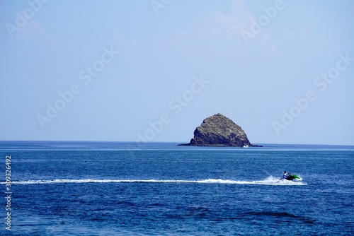 jet ski moving gas by rock island in the sea © Morten H