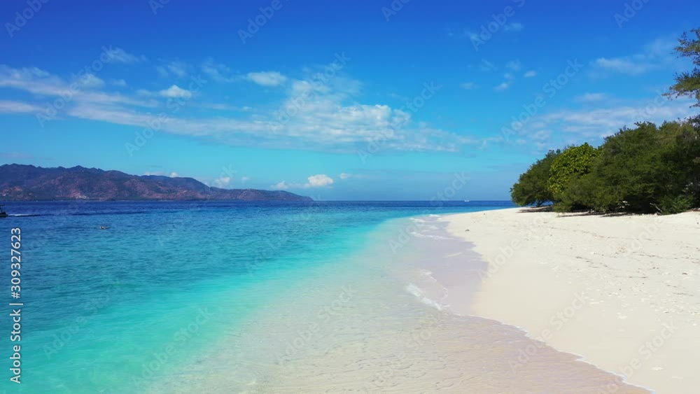 Vivid colors of beautiful seascape with blue azure sea washing white sand of exotic beach of tropical island with lush vegetation under bright blue sky with clouds Vivid colors of beautiful seascape with blue azure sea washing white sand of exotic beach of tropical island with lush vegetation under bright blue sky with clouds