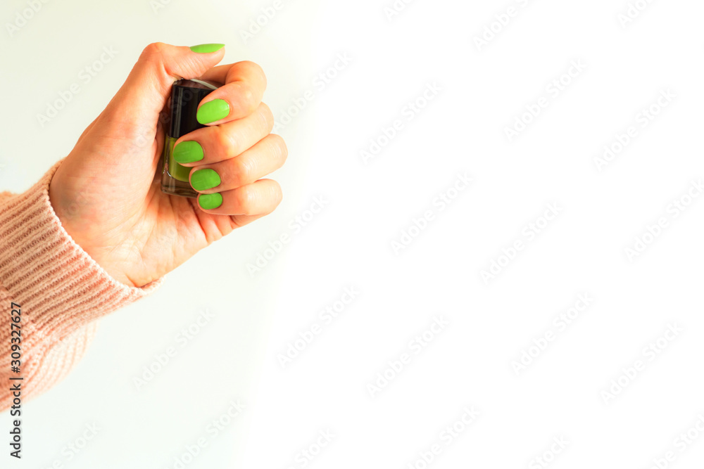Woman holding green mint nail polish bottle of same color of the manicure in hand. White background copy space. Beauty concept, pastel colors Woman holding green mint nail polish bottle of same color of the manicure in hand. White background copy space. Beauty concept, pastel colors