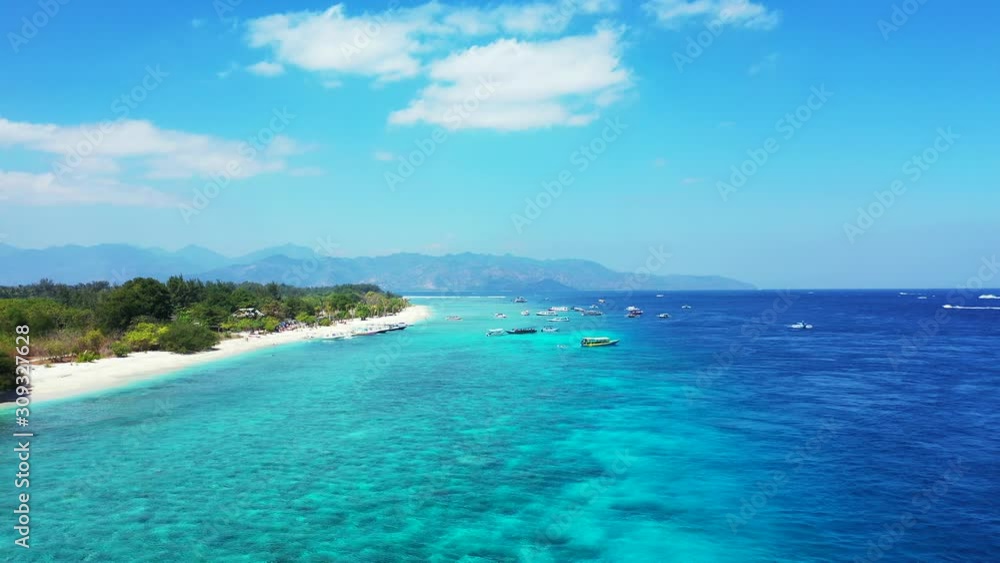 Paradise tropical island with pristine white sandy beach washed by blue turquoise water of calm lagoon under bright sky with white clouds in Bali Paradise tropical island with pristine white sandy beach washed by blue turquoise water of calm lagoon under bright sky with white clouds in Bali