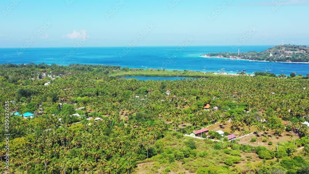 Tropical island with lush vegetation and palm trees forest around houses and hotels for vacations in Indonesia, surrounded by blue turquoise sea water Tropical island with lush vegetation and palm trees forest around houses and hotels for vacations in Indonesia, surrounded by blue turquoise sea water