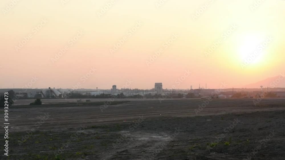 Industrial factory with warm orange sunset sky, Large empty area for industrial factory Industrial factory with warm orange sunset sky, Large empty area for industrial factory