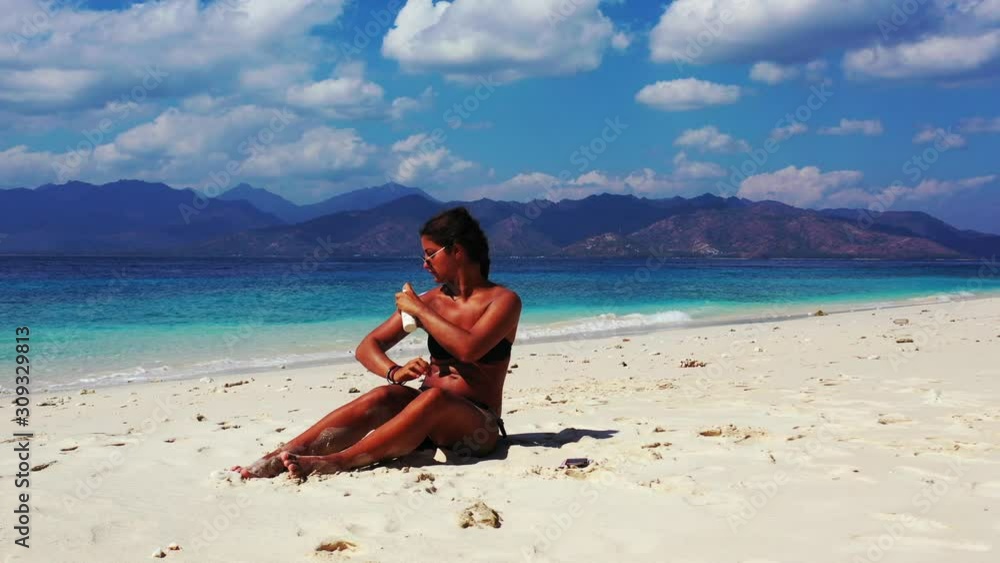 Attractive young woman applying sun protection oil spray. Beauty and health, skincare on the summer vacation Attractive young woman applying sun protection oil spray. Beauty and health, skincare on the summer vacation