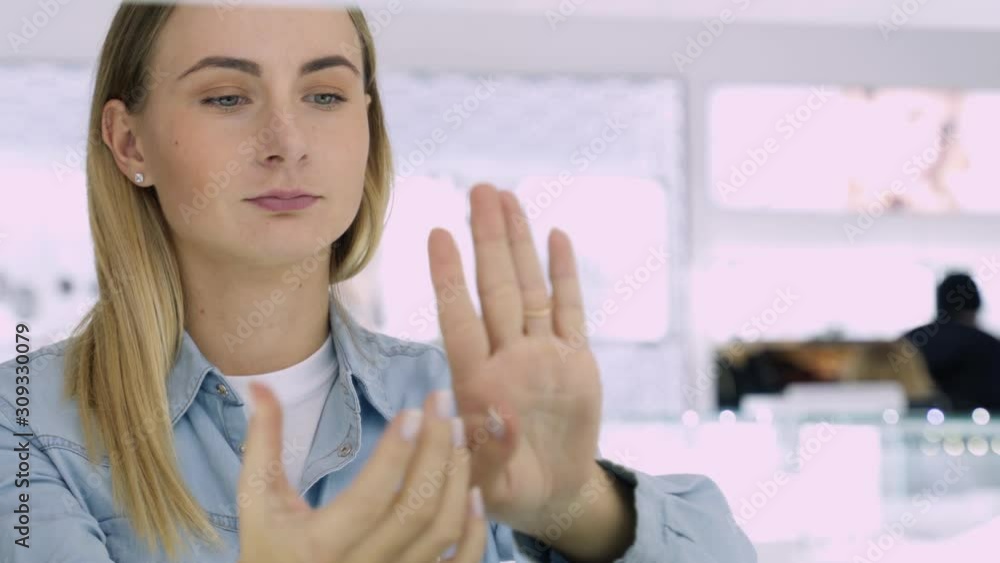 Shot of attractive young woman out shopping for jewelry. Girl lookin at he hand trying to choose rings.