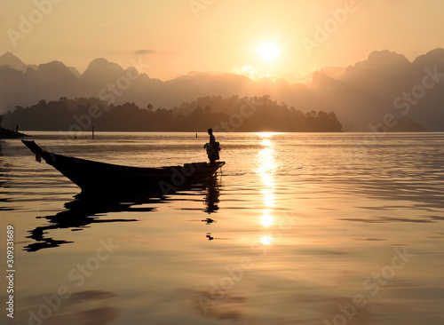 Silhouette scene of long tail boat during morning sunrise in Ratchaprapha Dam at  Khao Sok National Park, Surat Thani, South of Thailand. © maemanee