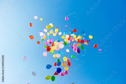 Flying balloons in blue sky with clouds