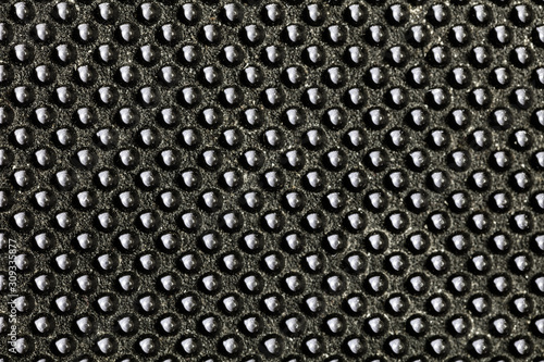 Black bumpy rubber surface used as a background. Black and white texture of rubber material with copy space. Bubble dots background pattern. Studio macro photography.