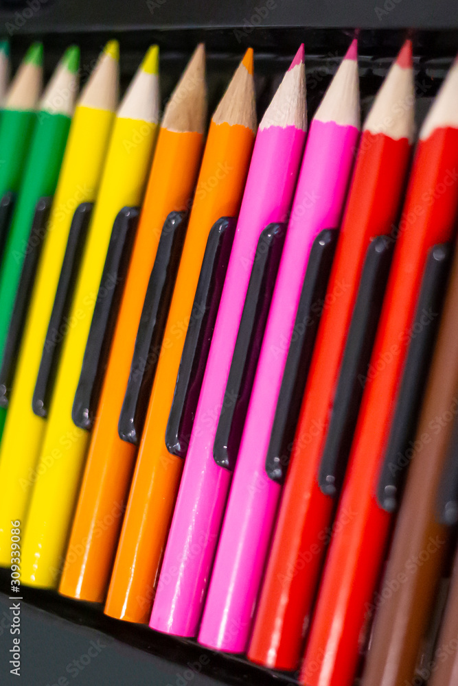 Set of bright wooden colored pencils laid out in a row with a dark background. Set of bright wooden colored pencils laid out in a row with a dark background.