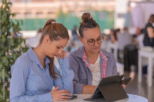 Two women busy while checking phones