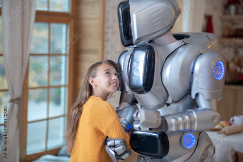 Cute girl in orange shirt feeling comfortable with her house robot photo