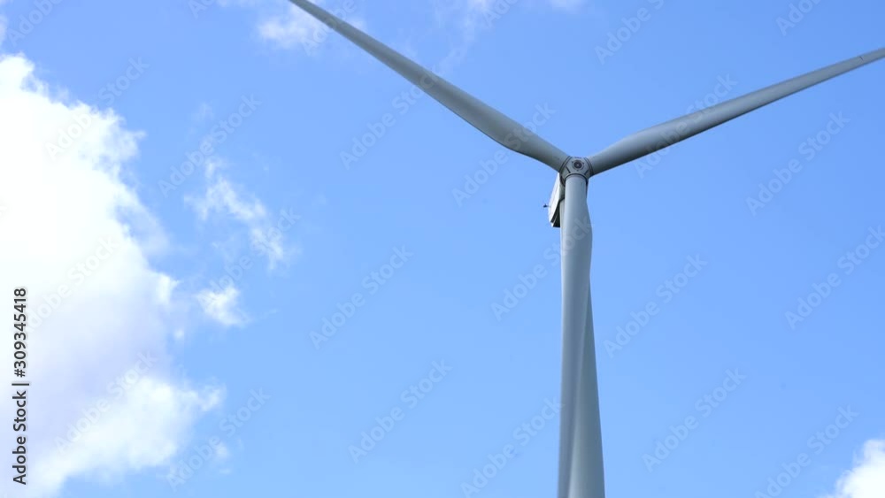 Time-lapse static shot of wind turbine blades spinning in the wind with summer blue sky background Time-lapse static shot of wind turbine blades spinning in the wind with summer blue sky background