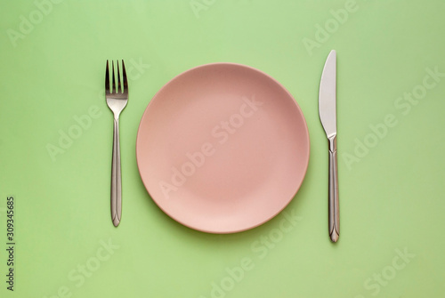Obraz na plátně Empty pink plate with utensils on green