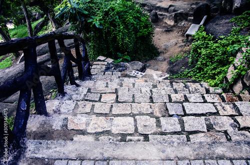 Old stone stairs in the park with wooden railing. Outdoors stone steps. Pilgrimage to the ancient shrines. © Irina