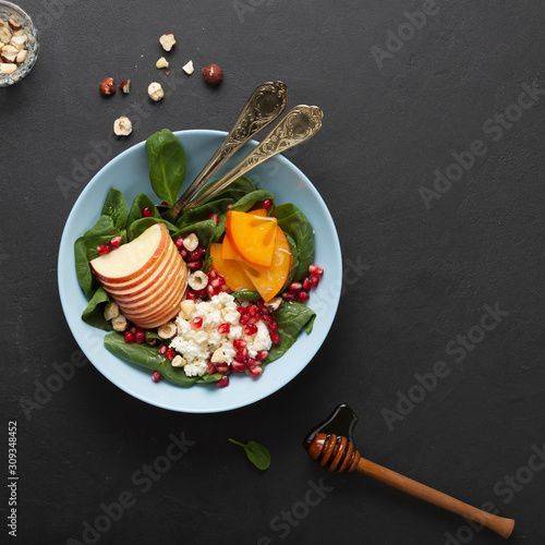 A bowl of healthy food. Fruits with spinach and cottage cheese are seasoned with honey and nuts. Organic food.