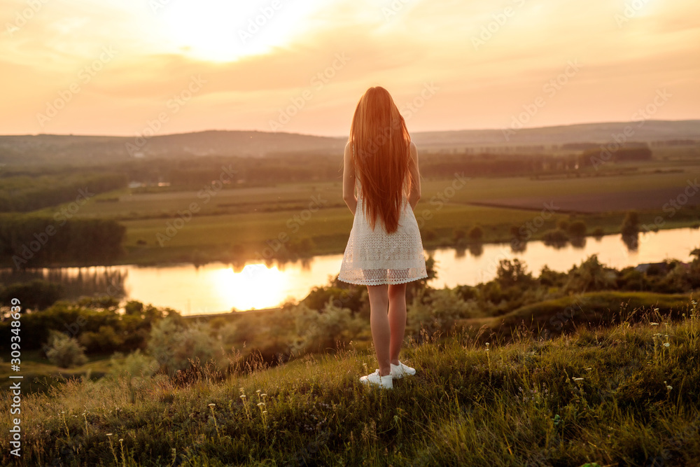 Unrecognizable young woman admiring sunset near river