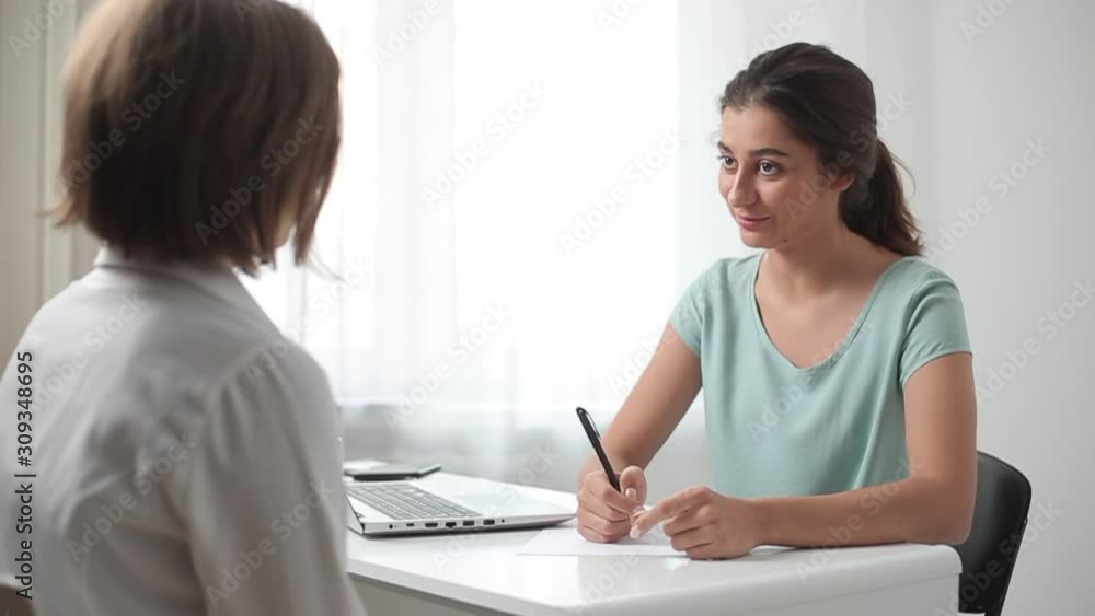 Indian young woman talking to a female customer. Friendly Asian girl advises business women. Indian young woman talking to a female customer. Friendly Asian girl advises business women.