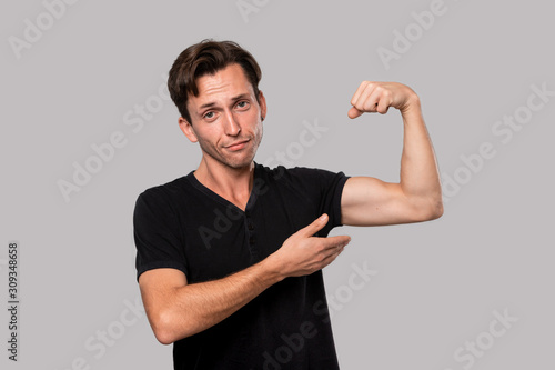 Handsome man pointing at his muscle bicep.