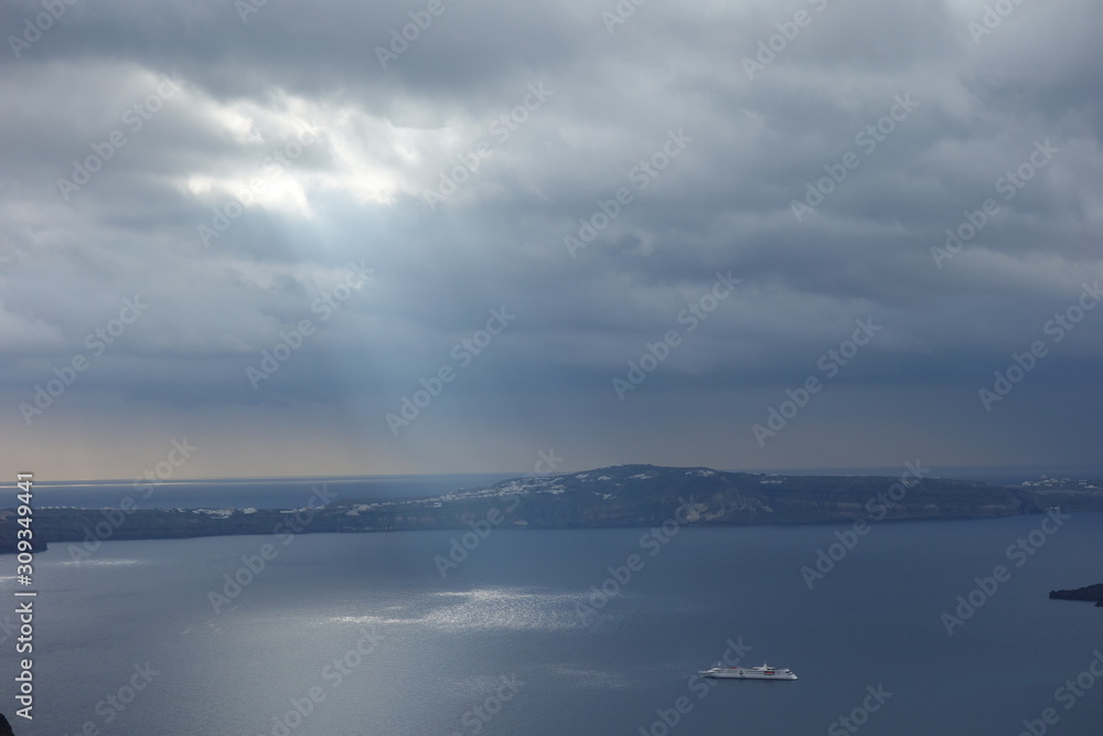 a spotlight in the middle of the ocean, next to the coast and a ship