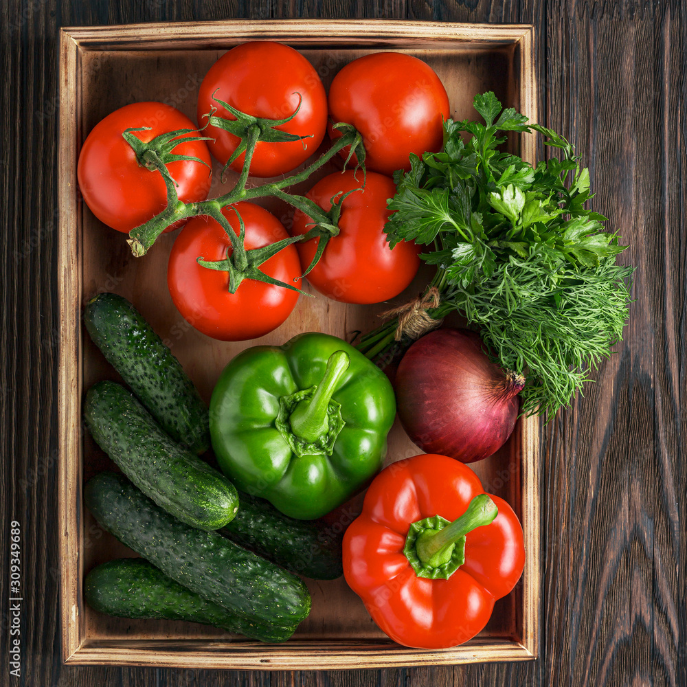 Fresh and juicy vegetables in a wooden box. Vegetable Salad Ingredients. Cucumbers, tomatoes, paprika, onions, herbs