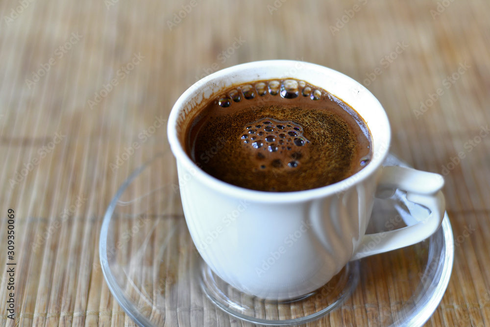 Fototapeta premium White cup of coffee on the bamboo napkin