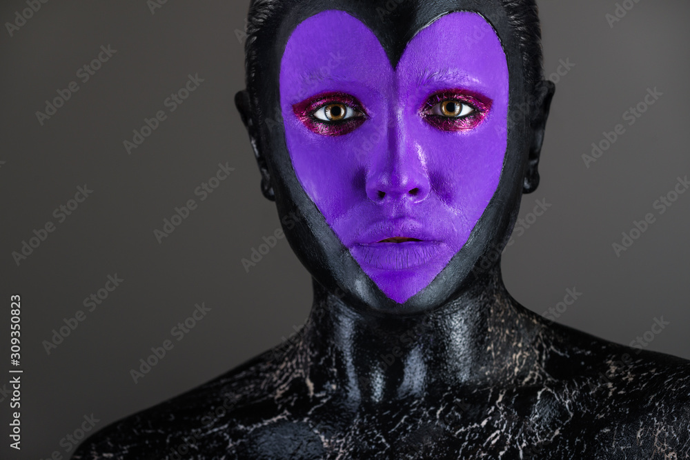 Close-up portrait of a beautiful woman with body art on her face in black color with purple heart on a black background. Concept of hidden pain and fears. Phobias and doubts concept. Advertising space