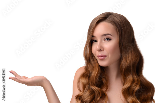Portrait of beautiful girl with long shiny wavy hair showing product, presenting hand. Perfect Fresh Clean Skin. Youth and skin care concept. Copy space