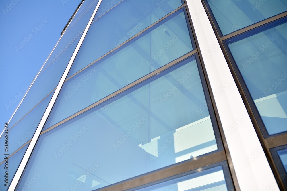Modern office building wall made of steel and glass with blue sky Modern office building wall made of steel and glass with blue sky