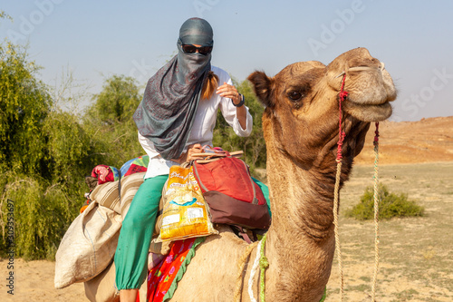 A woman on a camel safari in the Thar desert close from Jaisalmer, India