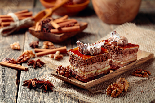 Layered cakes with spices and nuts on a  wooden table.