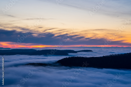 Germany, Magical aerial view above endless fog clouds covering valley of swabian jura nature landscape at sunset with orange sky near stuttgart on mountain breitenstein