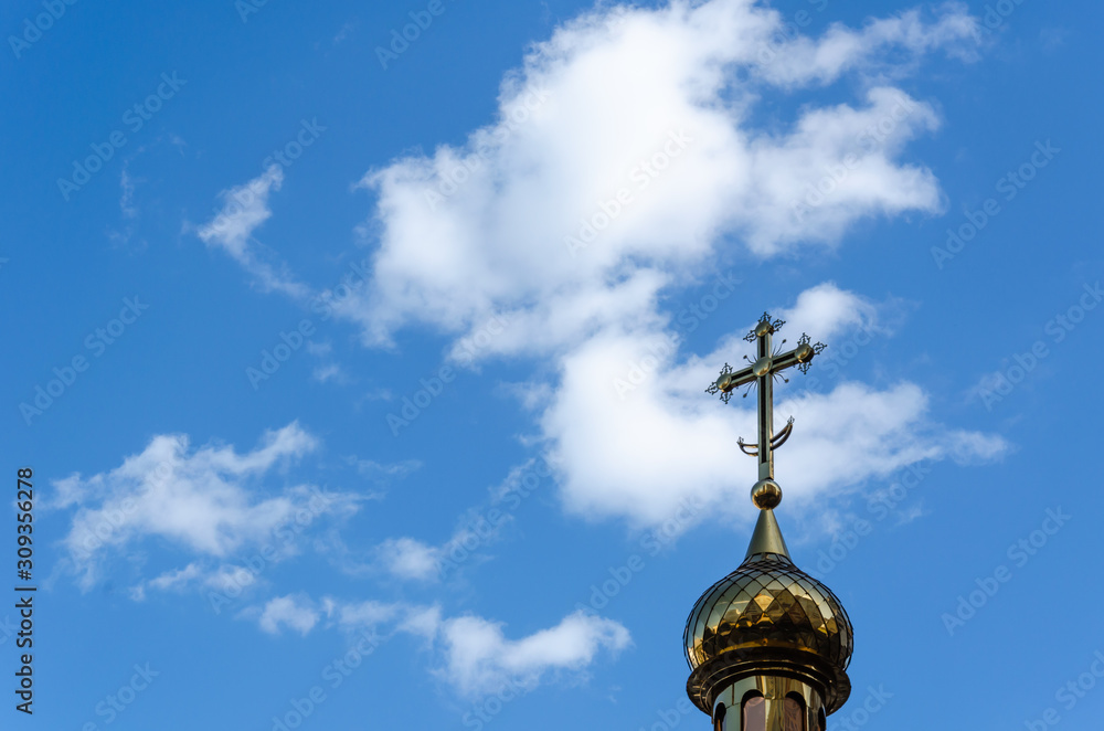 Golden dome with a cross of the Orthodox Church against the blue sky. Outdoors. Religion concept. Copy space