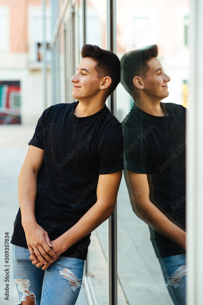 Fototapeta premium Young man leaning on a window pane.