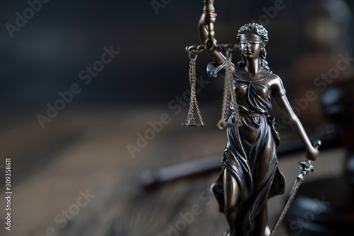 Justice concept. Themis statue on the rustic wooden table and the dark background.