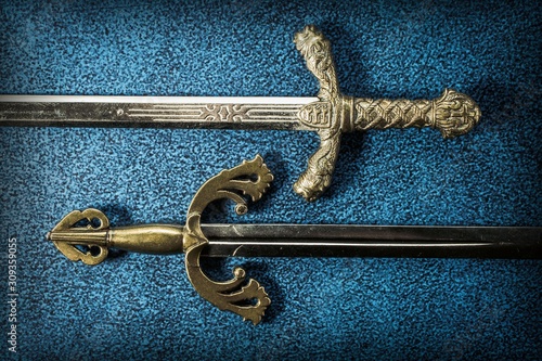 Photography Two hilt of knightly swords close-up on a dark blue background