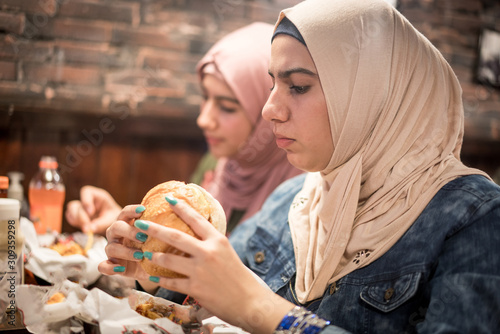 Arab girls at fast food restaurant eating burger