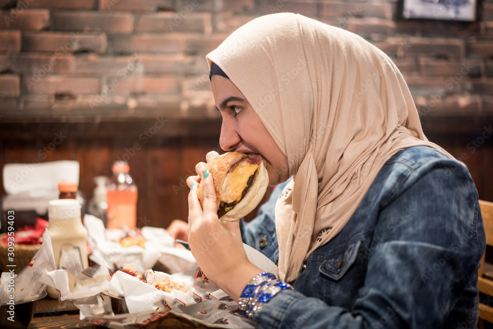 Arab girls at fast food restaurant eating burger