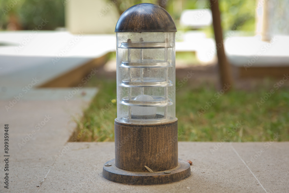 Lamp set on a wood on a high ground . small lantern in a garden on the ground . Lighting ground lamp street mounted on a green lawn in a park .