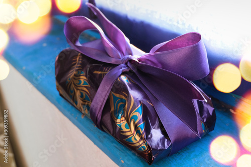 Purple and gold wrapped gift for Christmas on blue wooden board photo