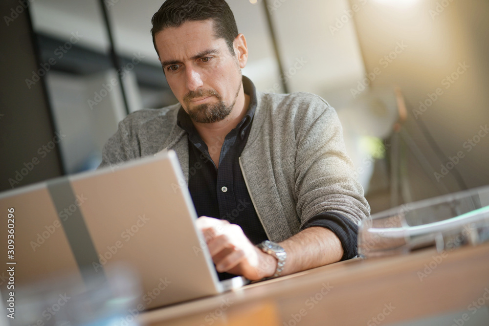 Fototapeta premium Man using laptop computer in co-working office