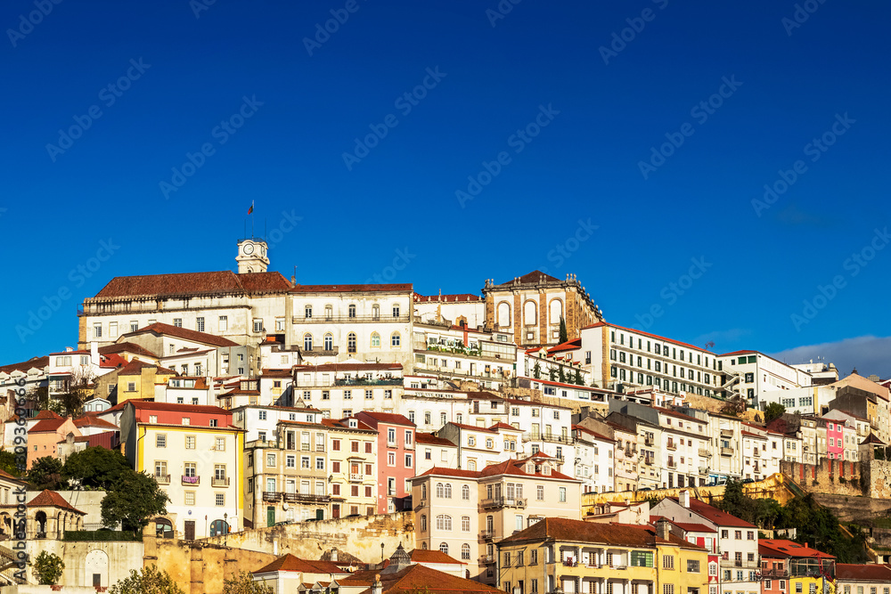 View of the high of Coimbra, Portugal, with its old houses up the hill to the University Tower on a sunny day with blue sky.