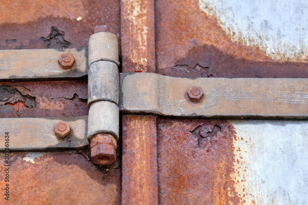 Big rusty steel hinge holding together iron plates that are rusting through. Seen in Bavaria, Germany in December. Big rusty steel hinge holding together iron plates that are rusting through. Seen in Bavaria, Germany in December.