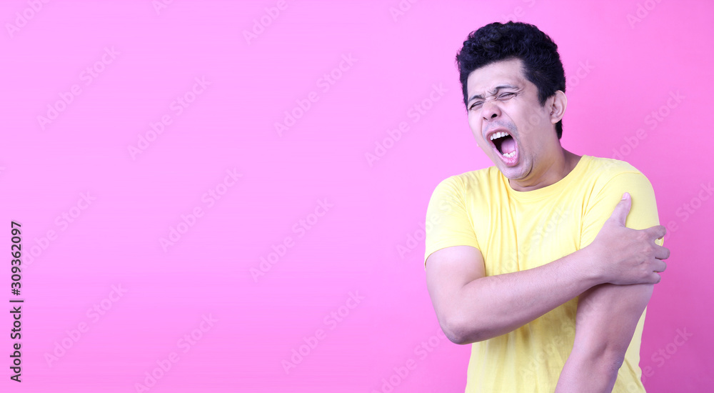 Portrait of A Handsome Asia man, holding his shoulder in pain on pink background in studio With copy space. Portrait of A Handsome Asia man, holding his shoulder in pain on pink background in studio With copy space.