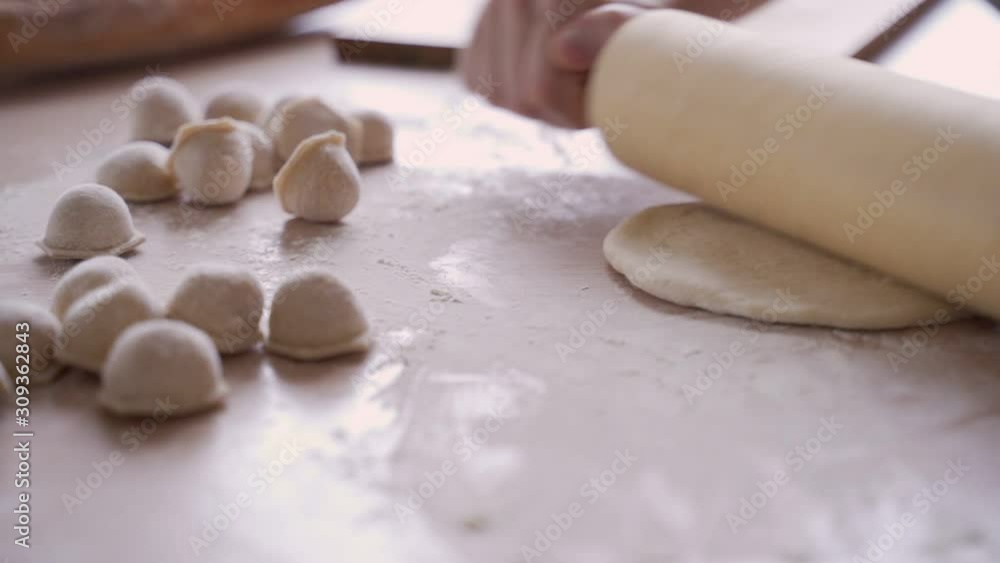 Rolling the dough for dumplings. The housewife rolls the dough with a rolling pin. Rolling the dough for dumplings. The housewife rolls the dough with a rolling pin.
