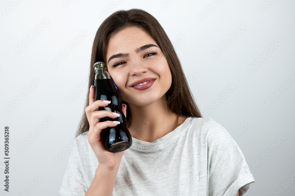 young attractive woman touching her face with bottle of soda drink with smile on her face on isolated white background dietology and nutrition young attractive woman touching her face with bottle of soda drink with smile on her face on isolated white background dietology and nutrition