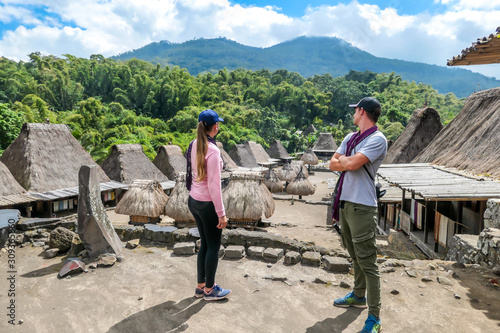 A couple with a purple scarfs admiring the Beno village in Flores, Indonesia. There are many small houses behind him. Each house is made of natural parts like wood and straw. History and tradition photo