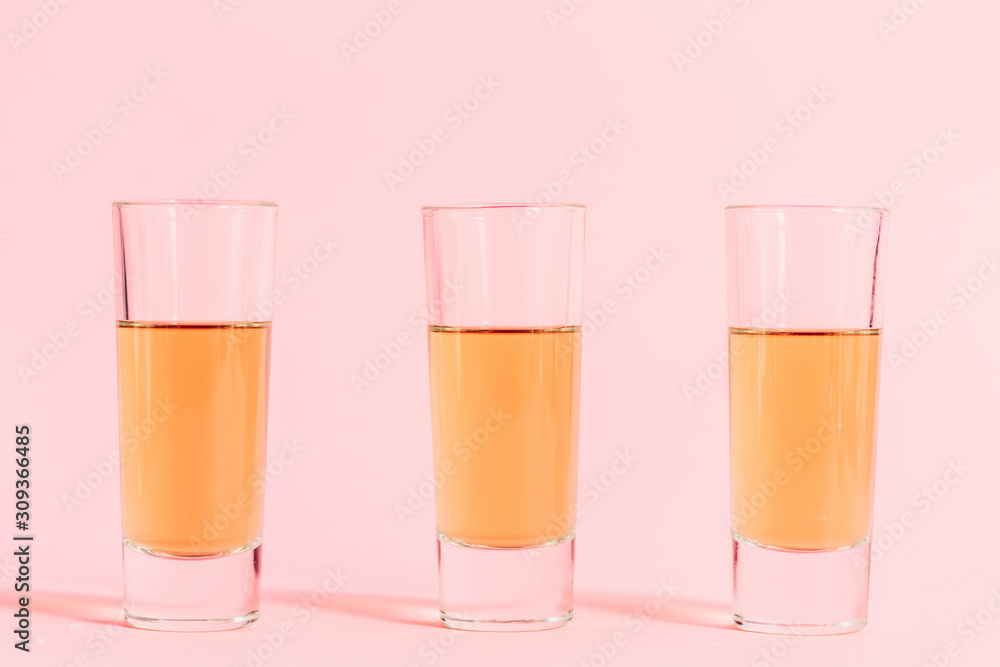 three shots with alcohol in row on pink background three shots with alcohol in row on pink background