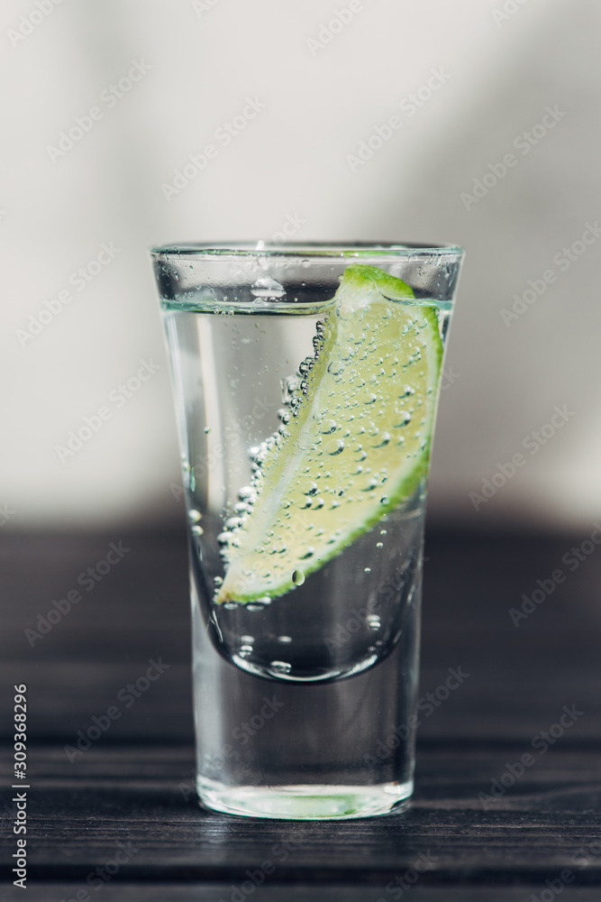 close up view of fresh tequila with lime on wooden surface close up view of fresh tequila with lime on wooden surface