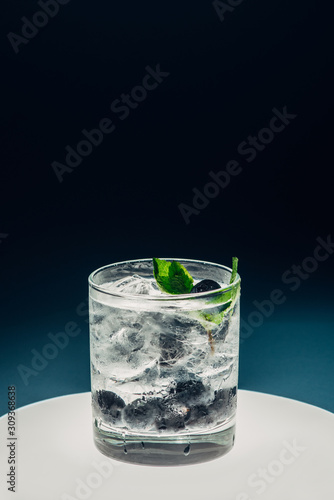 refreshing lemonade with ice and blueberries on illuminated circle on black background