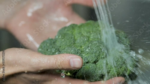 Washing broccoli cabbage under running water, close-up