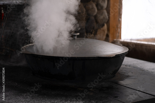 Preparation of shurpa in a cauldron on a Russian stove on an open fire.